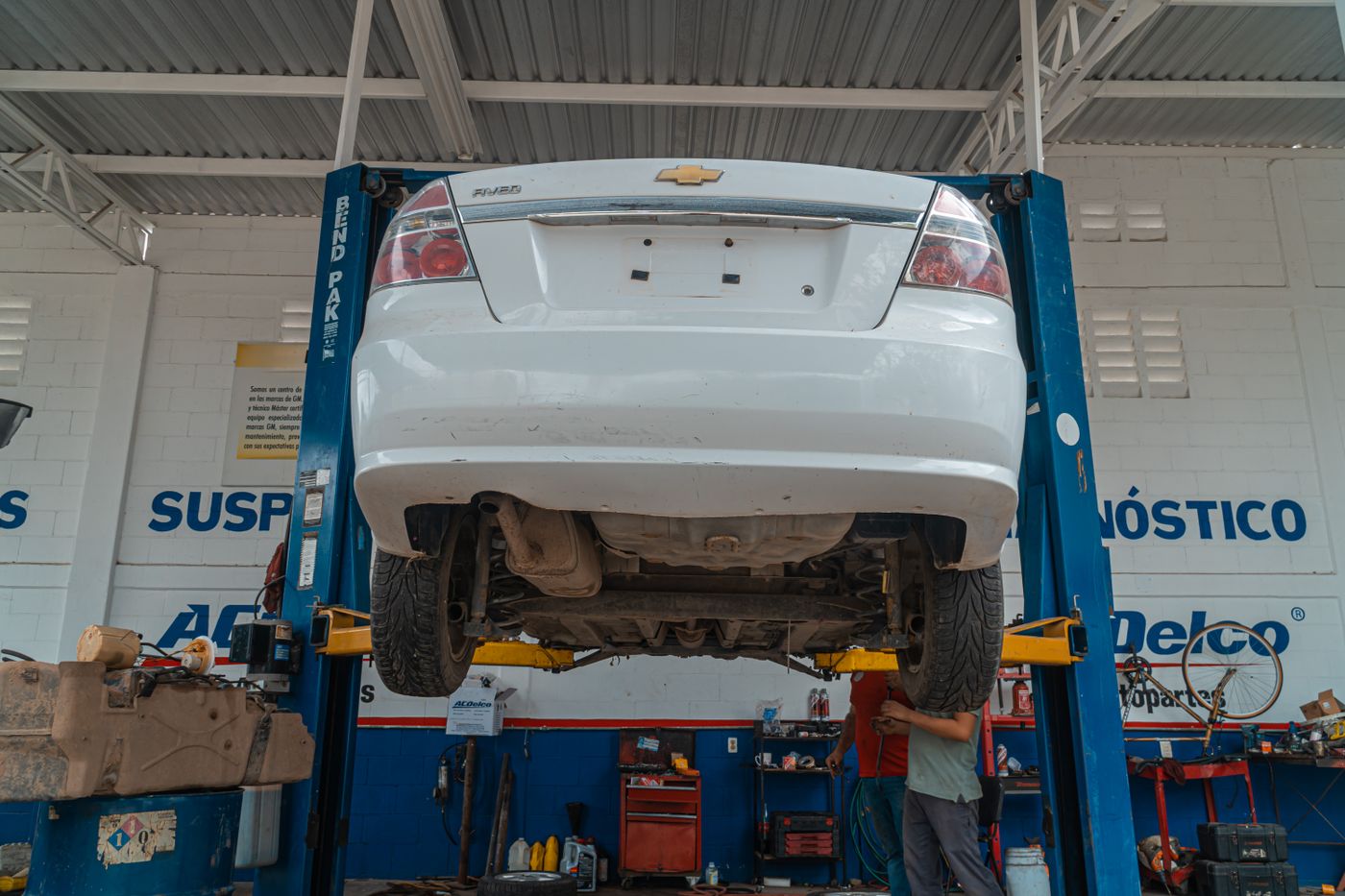 A car raised on a two-post ramp in a working garage